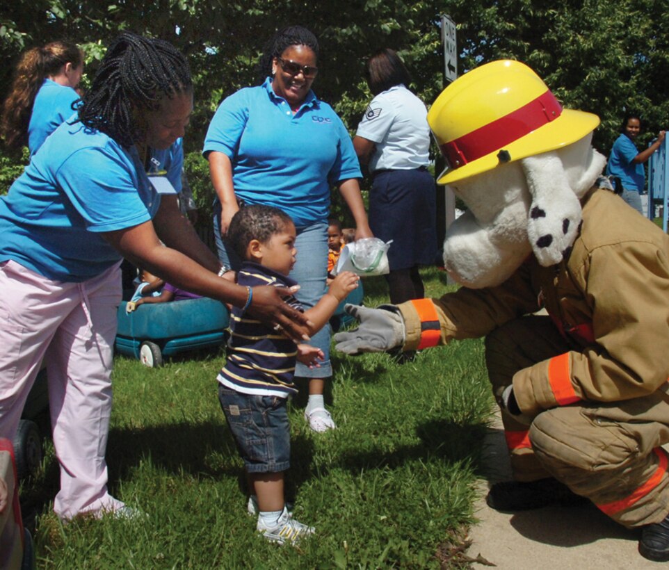 Gloria Williams, left, CDC II program assistant, helps Jonathan Coar, 1, son of Tech. Sgt. Nyeisha Coar, Air Force District of Washington project manager, greet Sparky the Fire Dog, as co-worker, Velma Harrison, observes. (U.S. Air Force photo/ Bobby Jones)