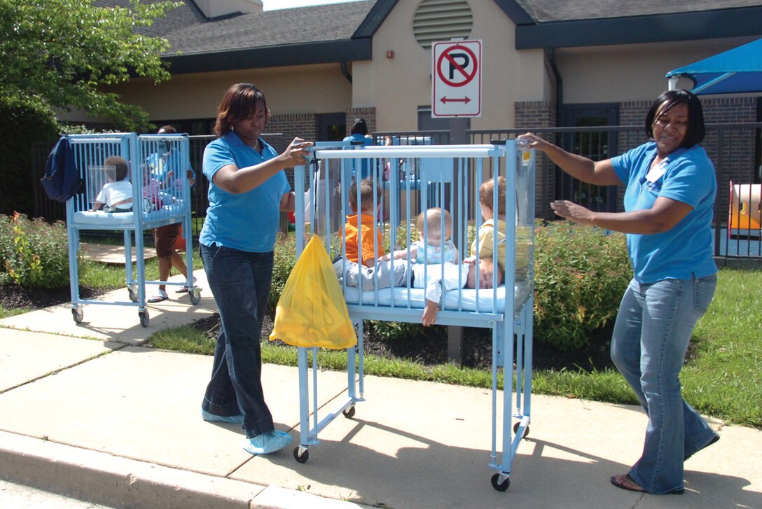 Tawanda Fowler, Child Development Center II program assistant, left, and co-worker, Tonda Ginn, right, carefully roll out a baby crib from the infant community during a fire drill held by the 316th Civil Engineer Squadron fire prevention team Monday. All CDCs and the Youth Center are required to have fire drills monthly. (U.S. Air Force photo/ Bobby Jones)