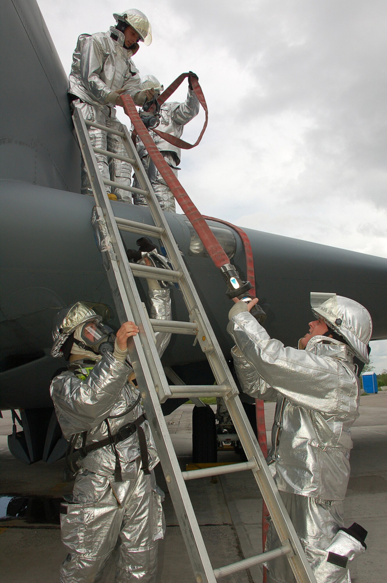 James Burchell steadies the ladder while Chris McDonald (from top left) and Terrence Ervin guide the fire hose down to Ryan Ranger after an on-ground emergency landing, or egress, exercise using a KC-135 Stratotanker on the flightline at Manas Air Base, Kyrgyzstan. The men are Sallyport Global Services-contracted firefighters with the 376th Expeditionary Civil Engineer Squadron here and are standing ready 24/7. (U.S. Air Force photo/Tech. Sgt. Phyllis Hanson)