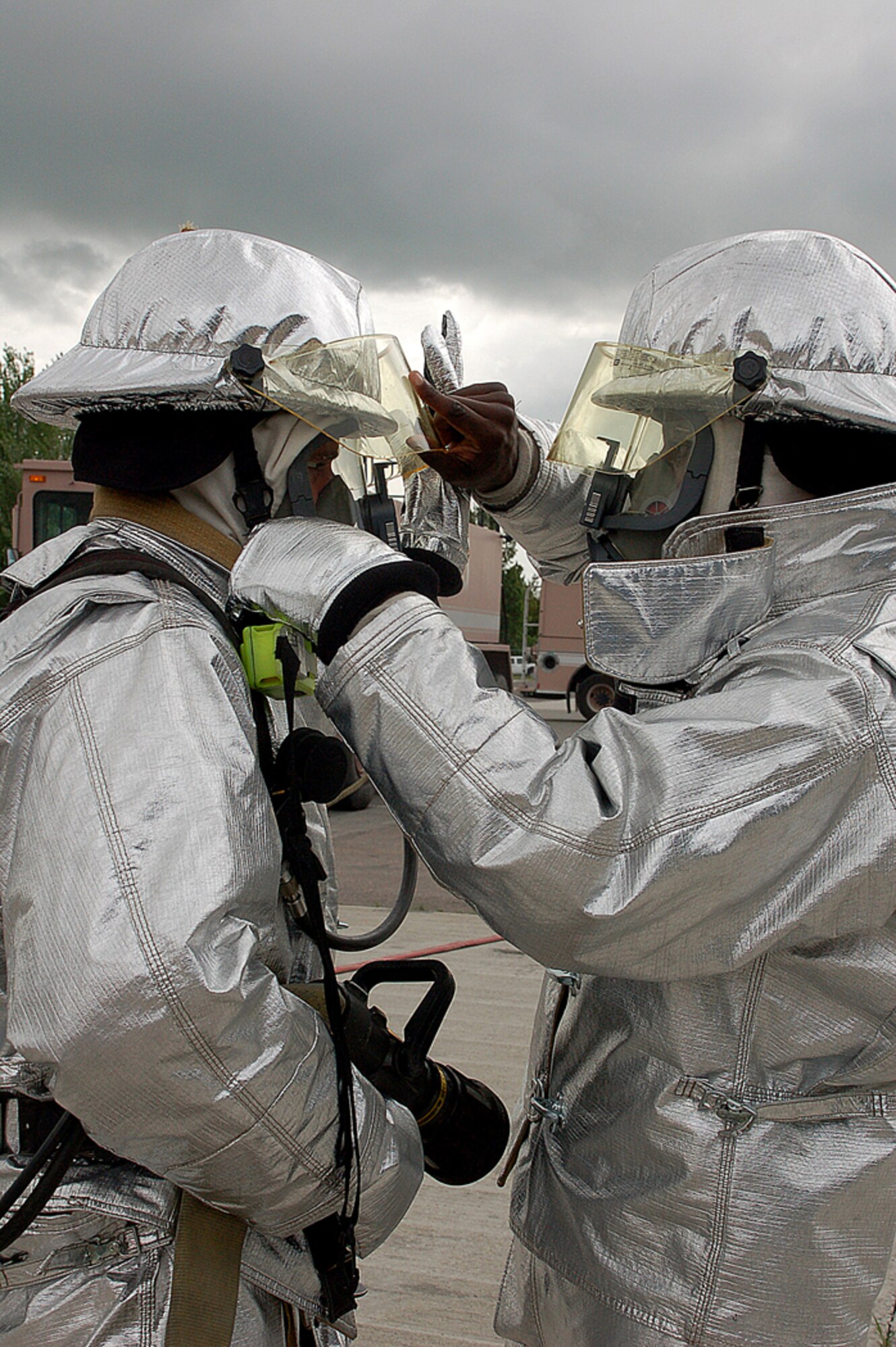 Prince Franklin (left) and Ryan Ranger do mask and gear checks before an on-ground emergency landing, or egress, exercise using a KC-135 Stratotanker on the flightline at Manas Air Base, Kyrgyzstan. Mr. Franklin and Mr. Ranger are Sallyport Global Services-contracted firefighters with the 376th Expeditionary Civil Engineer Squadron here and are standing ready 24/7. Mr. Franklin is originally from Diamond Bar, Calif., and Mr. Ranger is originally from Battle Creek, Mich. (U.S. Air Force photo/Tech. Sgt. Phyllis Hanson)