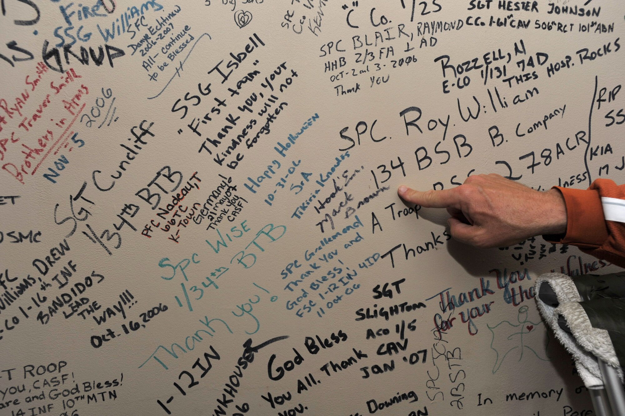 Mack Brown, head football coach at Texas University, points to wear he signed the "Warrior's Wall" at Joint Base Balad, Iraq. The wall is located at a medical treatment area of the base and is covered by the markings of wounded troops who have received treatment there. Brown and six other NCAA football coaches visited the base during Coaches Tour 2009, a morale-boosting mission organized by Morale Entertainment, LLC., in association with Armed Forces Entertainment. (U.S. Air Force photo/Tech. Sgt. Jason Schaap)