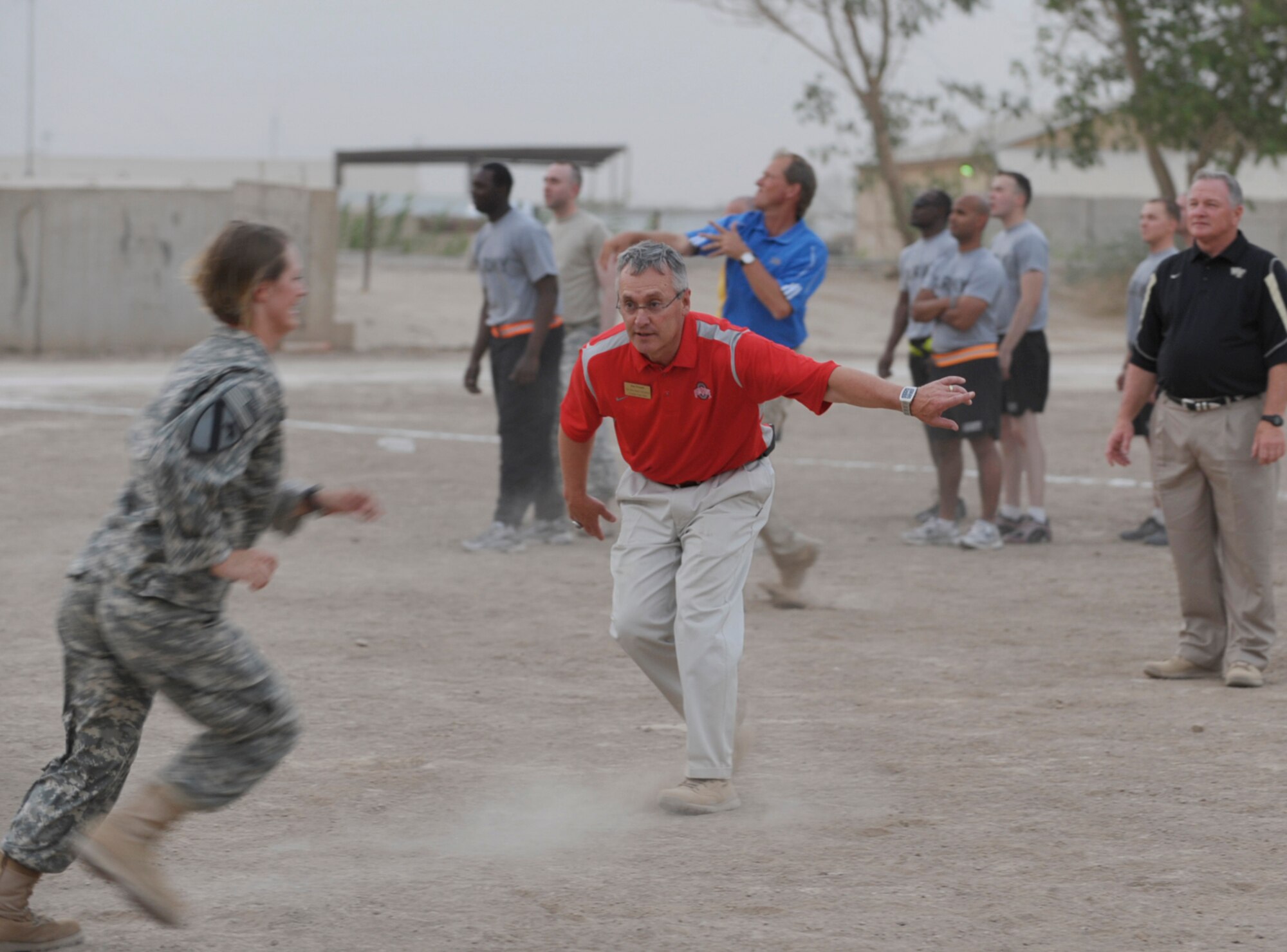 Jim Tressel, head football coach at Ohio State University, directs Army Capt. Christina Valentine during a football drill session at Camp Victory, Iraq, on June 1. To his right is Jim Grobe of Wake Forest, and throwing behind is Rick Neuheisel of UCLA, two more of the seven coaches participating in Coaches Tour 2009, a morale-boosting mission organized by Morale Entertainment, LLC., in association with Armed Forces Entertainment. A KC-135 Stratotanker from McConnell Air Force Base, Kan., was used to fly the coaches overseas. (U.S. Air Force photo/Tech. Sgt. Jason Schaap)