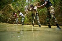 Members of the Royal St. Lucia Police Force's Special Service Unit make their way across a stream using measuring sticks while learning swift-water rescue procedures being taught by U.S. Air Force pararescuemen June 5 during Operation Southern Partner at La Toc, St. Lucia.  Operation Southern Partner is a long term commitment between U.S. and partner nations to share experiences, information, vital skills, tactics and techniques in preparation for future regional challenges that require cooperative solutions.  (U.S. Air Force photo/Staff Sgt. Bennie J. Davis III)