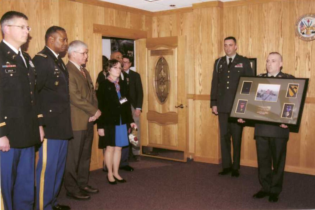 Army 1st Lt. Rob Lozzi, assistant operations officer at the Boston Military Entrance Processing Station, and Army Staff Sgt. Eric Sansoucie, Boston MEPS operations noncommissioned officer, prepare to mount a memorial plaque during a March 18, 2009, ceremony designating the 1st Lt. Andrew J. Bacevich Ceremony Room. Bacevichprocessed through the station's ceremony room in 2004 and was killed in Iraq in May 2007. Looking on, from left, are: Army Lt. Col Kevin Dunlop, Bacevich's former battalion commander; Army Col. Barrye L. Price, commander of U.S. Military Entrance Processing Command's Eastern Sector; and Bacevich’s parents, Andrew and Nancy Bacevich. Courtesy photo
