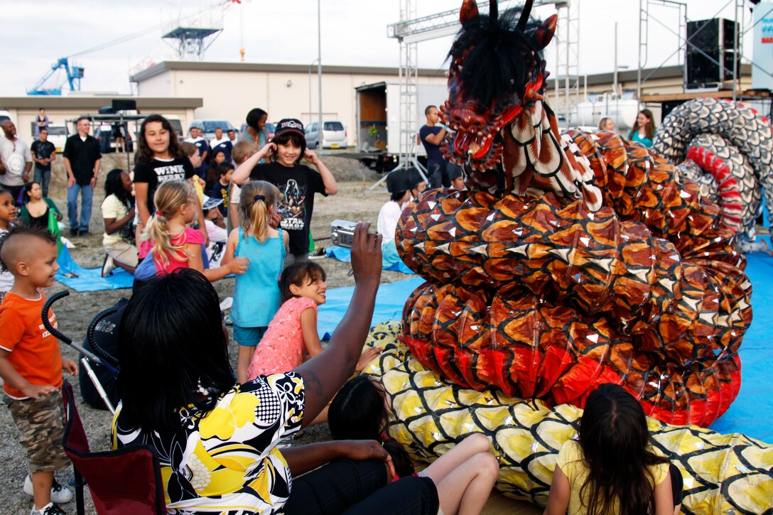 Marine Aviation Logistics Sqaudron 12 family members enjoy a cultural performance orchestrated by the Unada Group by the marina here June 6 during the MALS-12 Summer Bash. MALS-12 offered a fun atmosphere packed with cultural performances, live music, family games, a children’s train ride, barbeque, popcorn and cotton candy.