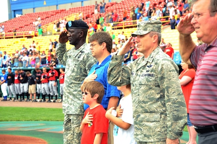 Patrons and service members, including Major General Abraham J. Turner, Chief of Staff, U.S. Strategic Command (left) render honors to the flag during the playing of the National Anthem during Military Appreciation Day at Rosenblatt Stadium, Omaha Nebraska on June 7th, 2009.  General Turner threw out a ceremonial first pitch and met with members of the Omaha Royals baseball organization.