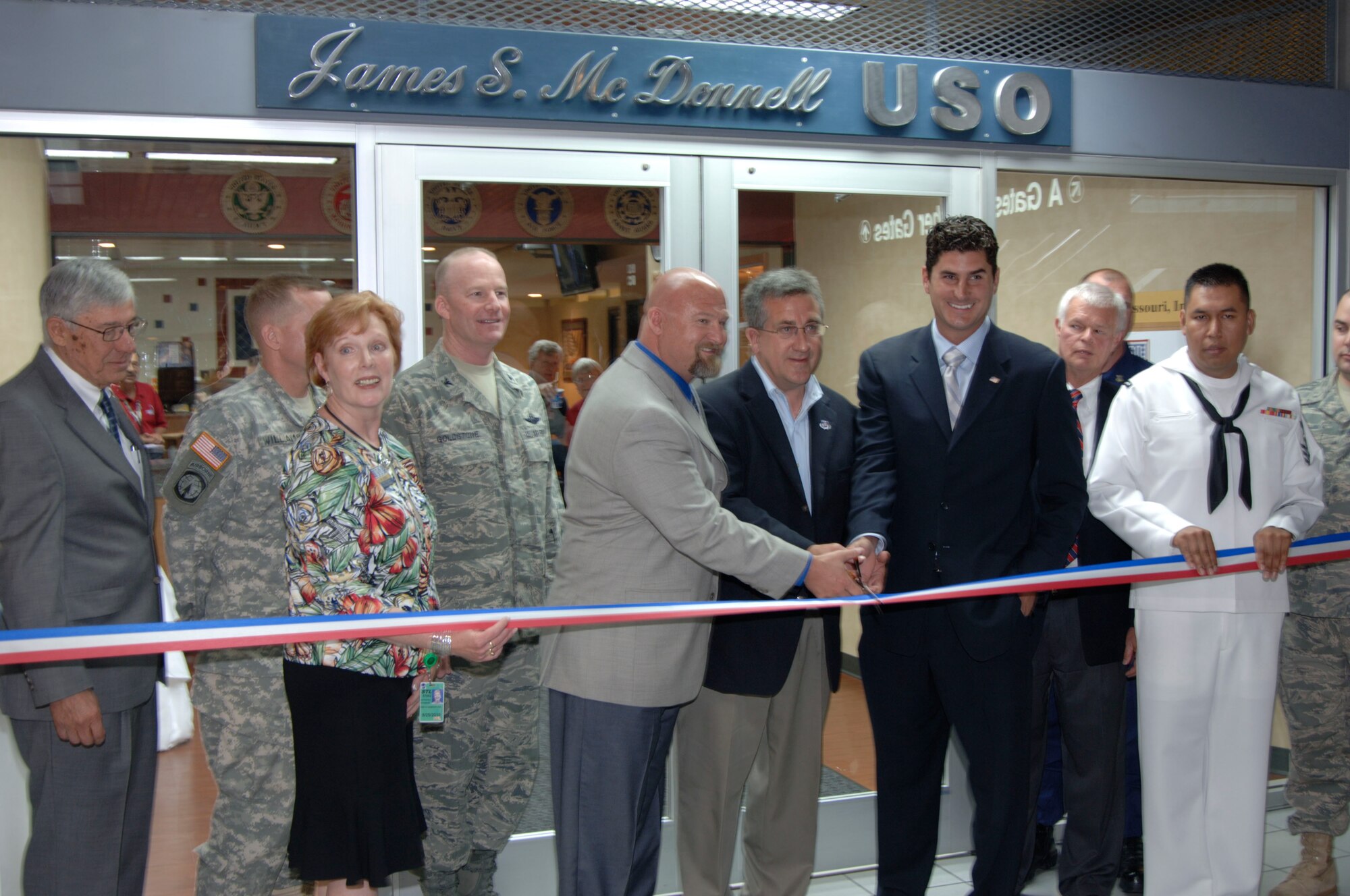 The USO at Lambert Airport in St. Louis re-opened June 3, 2009, after $300,000 worth of renovations gifted through the efforts of Dave Glover, 97.1 FM radio talk show host, and Marc Bulger, St. Louis Rams, who are pictured at center alongside honored guest and ardent USO supporter Rocky Sickmann. Citing that "nothing is too good for our troops"  Mr. Glover and Mr. Bulger headed fundraising effort for the renovations that feature a child play/sleeping area, cyber cafe, gaming room, expanded media room, remodeled canteen and dining area, changing room and a larger luggae storage area. Representing the base was Col. Gary Goldstone, 375th Airlift Wing commander, who said the USO is a home to our troops wherever it may be and thanked them for their continued support of the nation's servicemembers. (Photo by Karen Petitt/375 AW/PA)