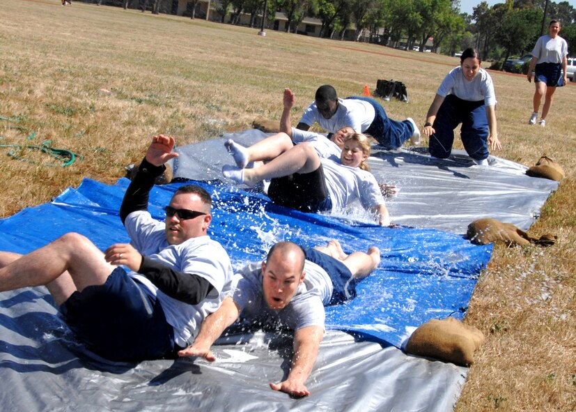 Front, from left to right; Senior Airman Zach Morris and Staff Sergeant Eric Tolon are followed down the slip and slide by team mates Airman First Class Te'Anna Drake, 1ST Lieutenant Angelique Mahdi, A1C Larame Carpenter and Airman First Class Imaya Rodriguez.  They are all members of the 60th Aerial Port Squadron and participated in Travis Sports Day 21 May 2009.  (U.S. Air Force photo by Civ/Nan Wylie)