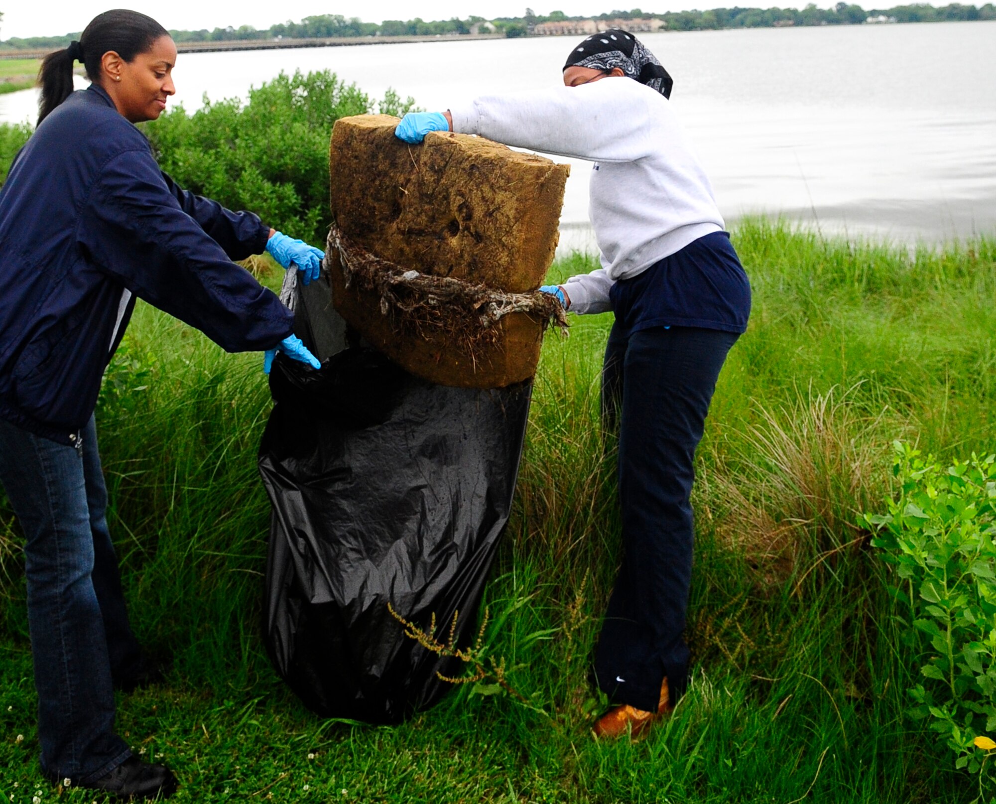 LANGLEY AIR FORCE BASE, Va. -- Staff Sgts. Korin Sarter and Desiree Lilley, 1st Medical Support Group Squadron, remove an old seat cushion from the Chesapeake Bay during the 21st Annual Clean the Bay Day here June 6. Volunteers from the 1st Fighter Wing and Air Combat Command collected 4,000 pounds of trash and debris during the Clean the Bay Day event. (U.S. Air Force photo/Senior Airman Dana Hill)