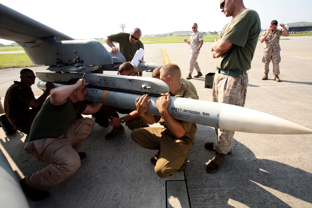 Marines with Marine Attack Squadron 211, out of the Marine Corps Air Station in Yuma, Ariz., mount an AIM-120 advanced medium-range air-to-air missile onto the wing of an AV-8B Harrier June 8, 2009, at Kadena Air Base in Okinawa, Japan. The squadron became the first Marine unit to launch the AMRAAM from a Harrier. VMA-211 is currently deployed with the 31st Marine Expeditionary Unit and is participating in Exercise Talisman Saber in Australia.(Photo by Lance Cpl. Jeffrey Cordero)