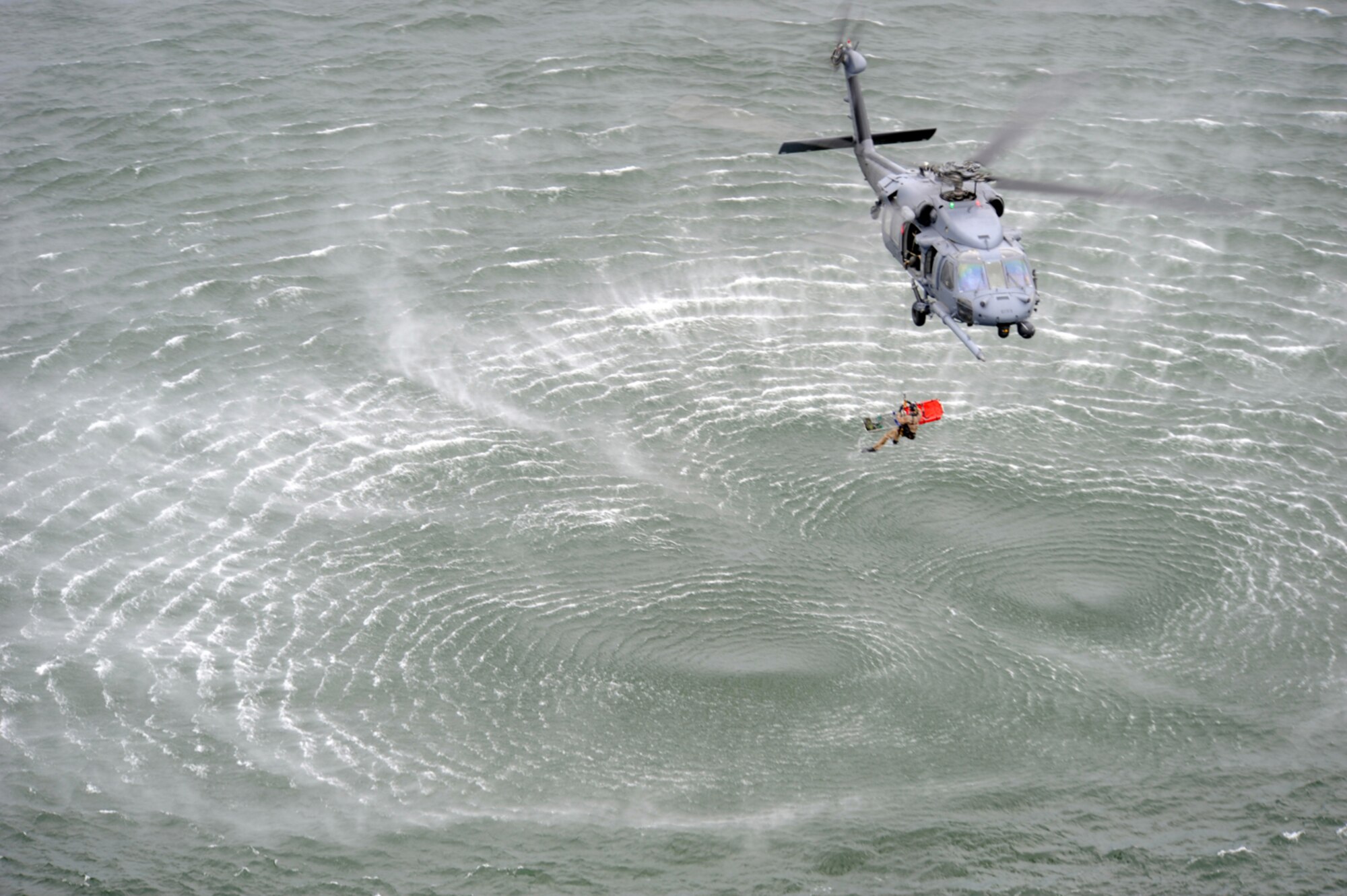 Master Sgt. Michael Atkins of the 48th Rescue Squadron is lowered to the water by Chief Master Sgt. Kenneth Price, 563rd Rescue Group superintendent, to rescue an injured survivor during Exercise Resolute Angel. The exercise, hosted by Laughlin Air Force Base, Texas, was conducted in preparation for the upcoming hurricane season. (U.S. Air Force Photo/Master Sgt. Heather Cabral)