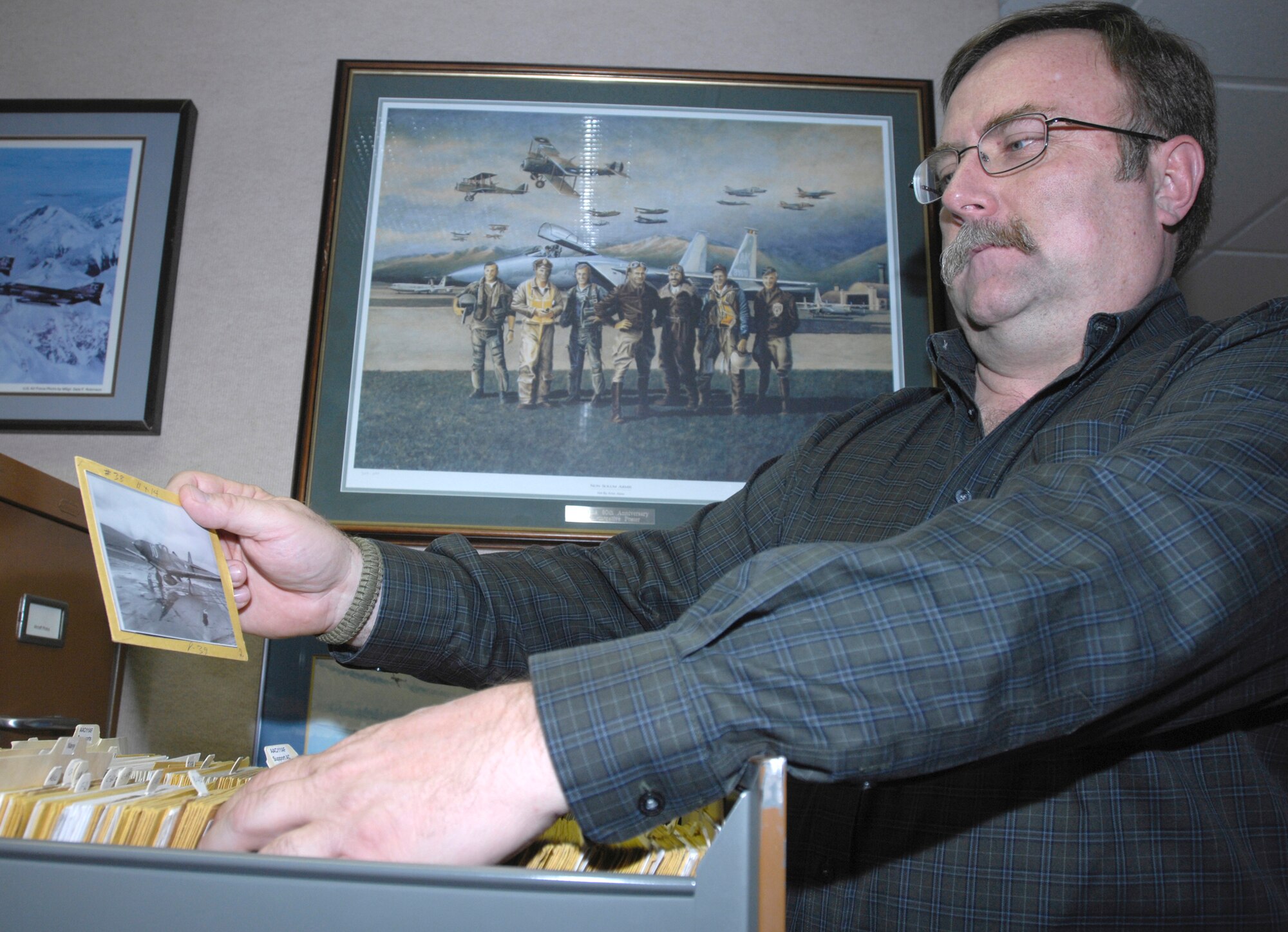 ELMENDORF AIR FORCE BASE, Alaska -- Doug Beckstead, 3rd Wing History Office, goes through a file of historical photos June 3, 2009. The photo he is holding is a P-39 on a trenched, sandy runway in the Aleutians. Beckstead and his co-workers received the 2009 John R. Burton Award for being the best history office in the Air Force. (U.S. Air Force photo/Airman 1st Class Christopher Gross) 