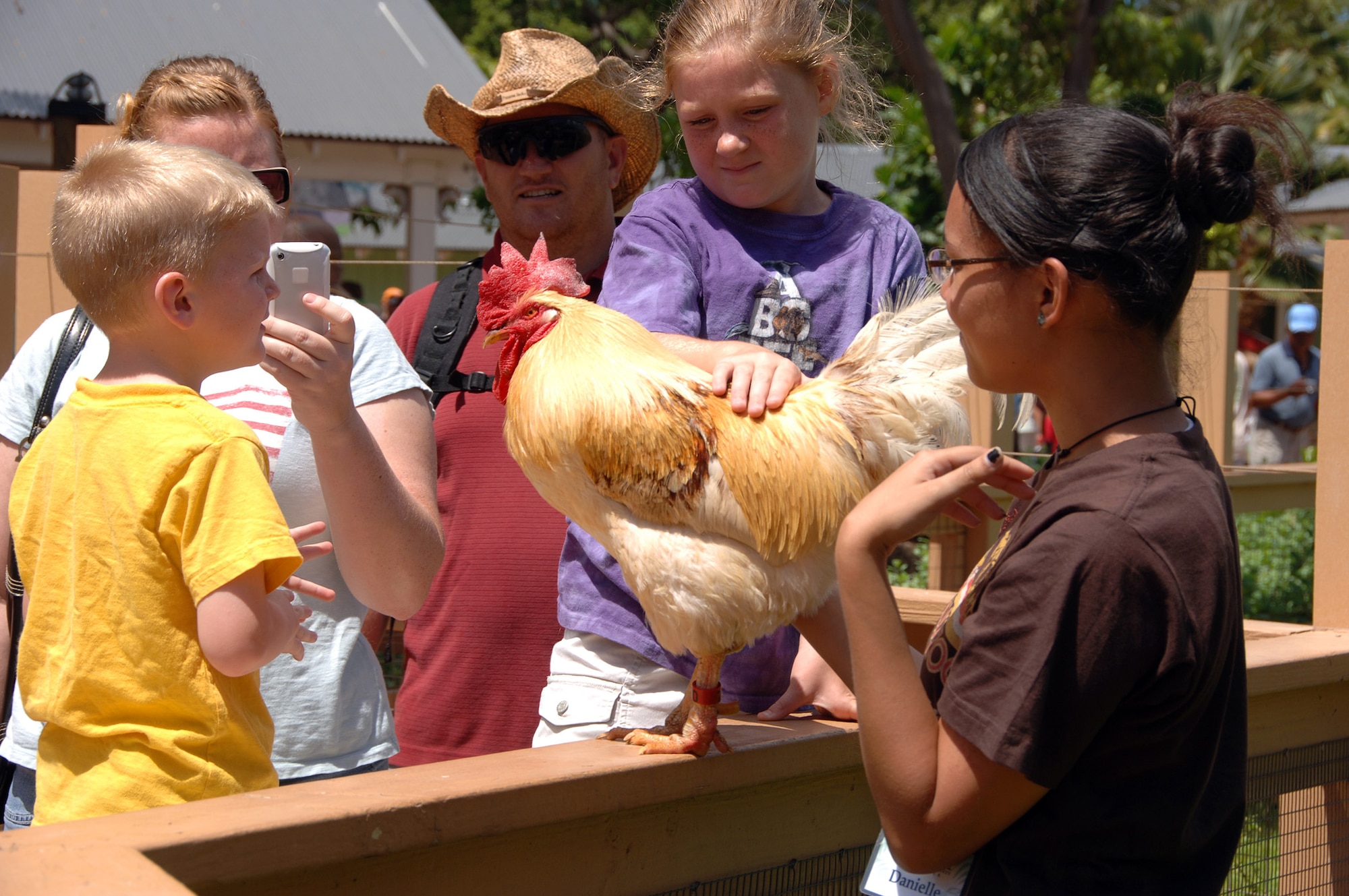 HICKAM AIR FORCE BASE, Hawaii – Emily Anderson (center), 4, and younger brother Zachary Anderson (left), 5, check out a rooster at the Kids Petting Zoo while zoo volunteer Danielle Clavier (right) assists during the Military Appreciation Day held June 6 at the Honolulu Zoo.  Emily and Zachary were accompanied by their mother, Angela Anderson (middle left), and their father, Sergeant Joshua Anderson (middle) of the Army National Guard Reserves at Barber's Point. (U.S. Air Force photo by Vanessa Perez)     