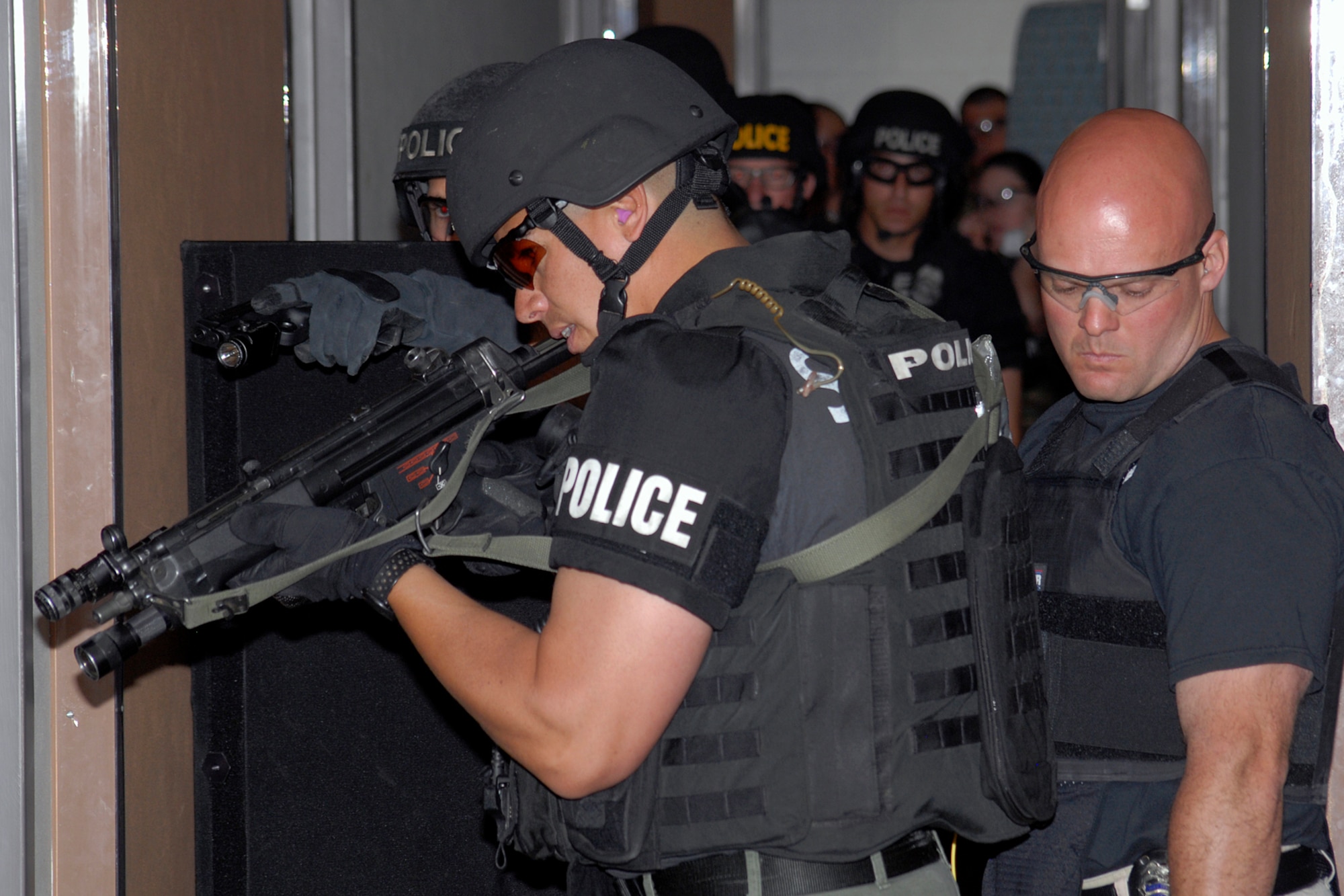 Local law enforcement officers prepare to enter a vacant Peterson dormitory room as part of a building search and clear exercise. Police from the Colorado Springs Police Department, El Paso County Sheriff, and the Federal Bureau of Investigation teamed with 21st Security Forces Squadron Airmen for a day of joint training. Peterson security forces Airmen and their civilian counterparts practiced a variety of policing skills including tactical team movements, search and clearing of rooms and buildings, hostage rescue operations, weapon tactics, rules of engagement and mission execution procedures. (Air Force photo by Larry Hulst)