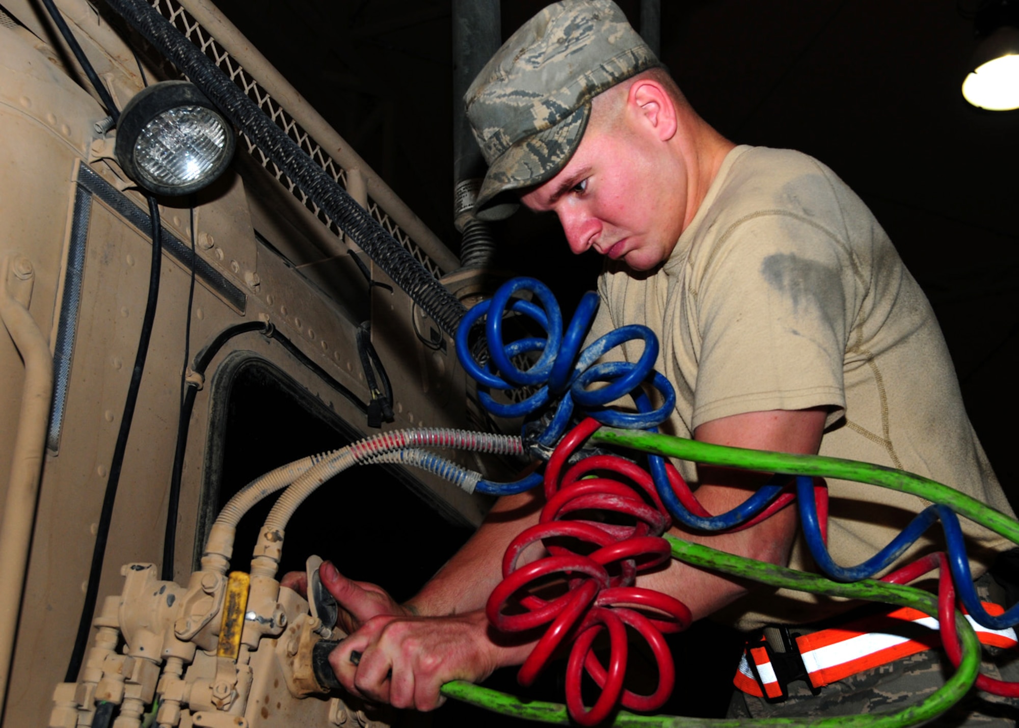 SOUTHWEST ASIA -- Senior Airman Charles Sarrazim, 586th Expeditionary Logistics Readiness Squadron vehicle maintainer, disconnects the lights and braking system hoses from a truck cab to untangle them at an Army base in Southwest Asia, June 8. The red hose is for the emergency brakes, the blue is for the regular service brakes and the green is the pigtail for the lights and anti-lock braking system. Airman Sarrazim is deployed from Malmstrom Air Force Base, Mont., and hails from Clyde Park, Mont. (U.S. Air Force photo/ Senior Airman Courtney Richardson)