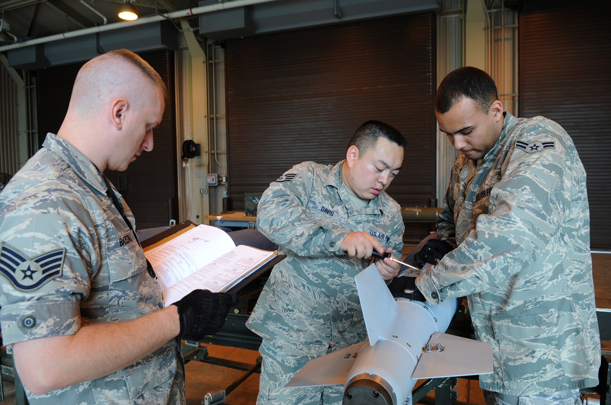 MISAWA AIR BASE, Japan -- Staff Sgt.  Robert Baarstad, Staff Sgt. James Davis and Airman 1st Class Michael Eiland, from the 35th Maintenance Squadron munitions flight, build a GBU-38 training round June 9, 2009. Misawa pilots dropped the first inert GBU-38 on Draughon Range May 13, 2009, expanding local training opportunities. (U.S. Air Force photo by Staff Sgt. Rachel Martinez)