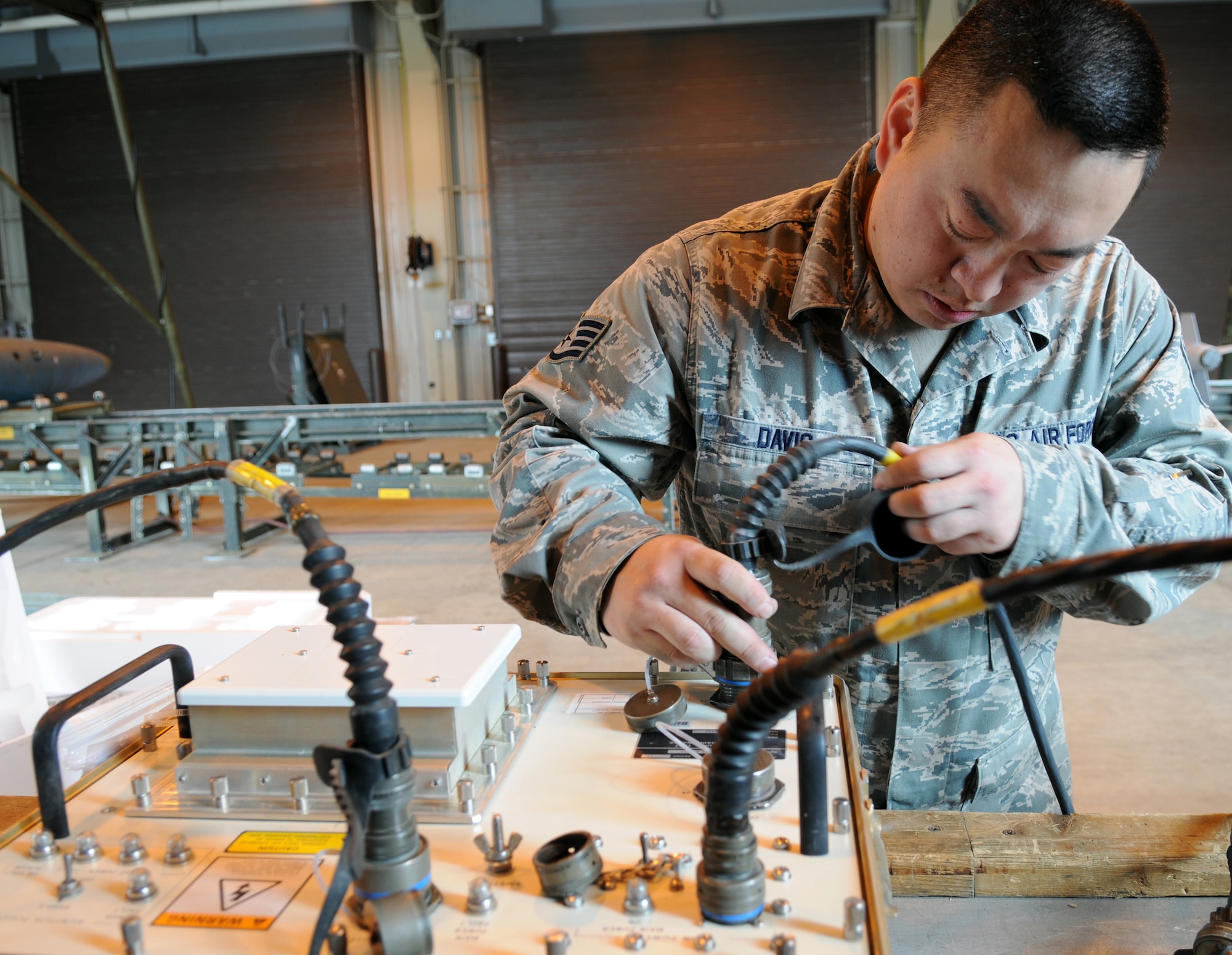 MISAWA AIR BASE, Japan -- Staff Sgt. James Davis, 35th Maintenance Squadron munitions flight crew member, connects cannon plugs on Common Munitions Bit/Reprogramming Equipment June 9, 2009. The CMBRE tests the working components of a joint direct attack munition's guidance system. The guidance system can be tested before or after the fin is attached to the munition. (U.S. Air Force photo by Staff Sgt. Rachel Martinez)
