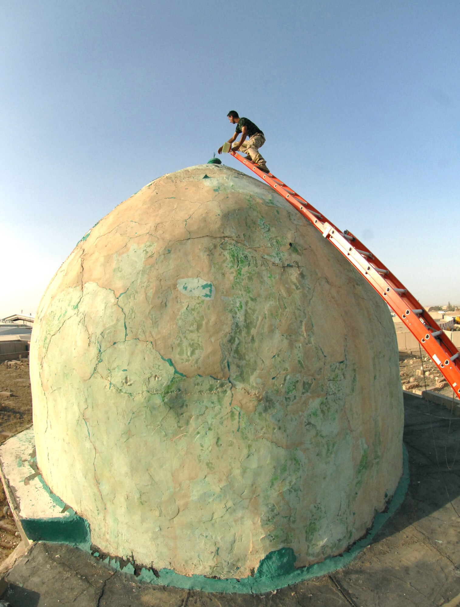 An Iraqi airman climbs to the top of the Sultan Saqi Shrine dome to paint the first coat of primer here May 13. Iraqi airmen painted the shrine's dome deep green. A coalition team restored two structures in the Sultan Saqi cemetery prior to the first official visit in almost three decades by Iraqi family members, friends and local leaders. (U.S. Air Force photo/Senior Airman Jessica Lockoski)