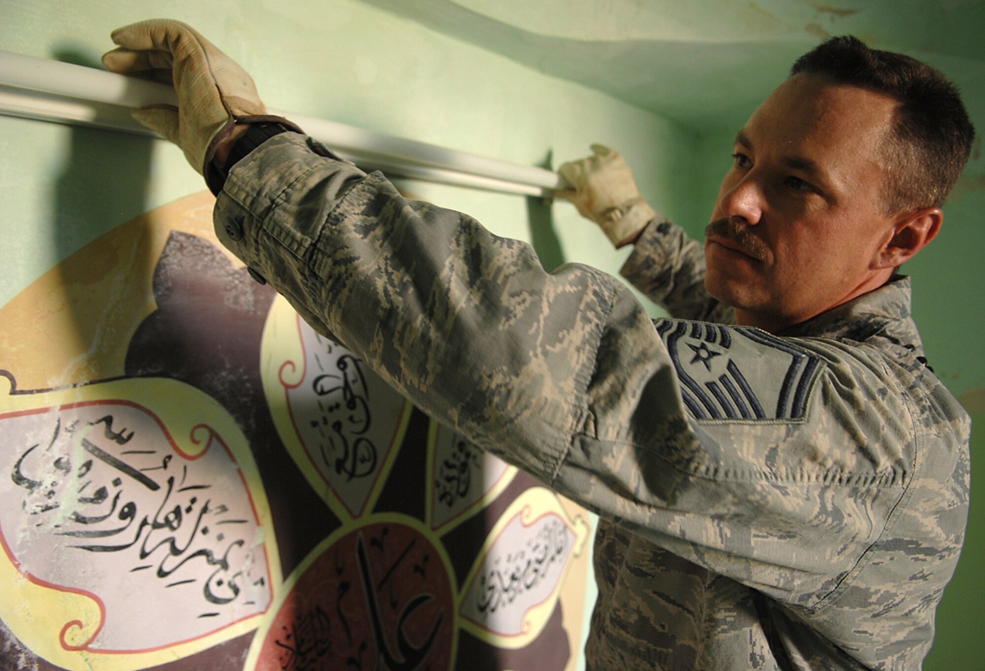 Senior Master Sgt. Gary Lytle, 506th Expeditionary Civil Engineer Squadron electrical systems superintendent, places a fluorescent light bulb into a fixture he repaired inside the Sultan Saqi Shrine. Sergeant Lytle provided temporary power to the shrine and repaired electrical outlets in its rooms prior to an official visit of Iraqi family members and local leaders in May. (U.S. Air Force photo/Senior Airman Jessica Lockoski) 