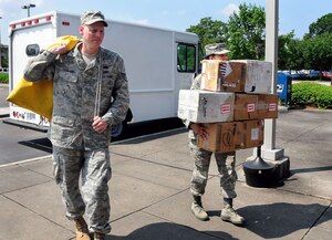 Staff Sgt. Trent Harland and Airman 1st Class Tiphani Curry transport a bag of official mail and seven packages from the back of their delivery truck on a morning mail run to the base clinic here June 9. The Official Mail Center staff supports wing and group level official mail delivery, pickup, mail sorting for the entire base and off-base mailings. Sergeant Harland and Airman Curry are with the 437th Communications Squadron.