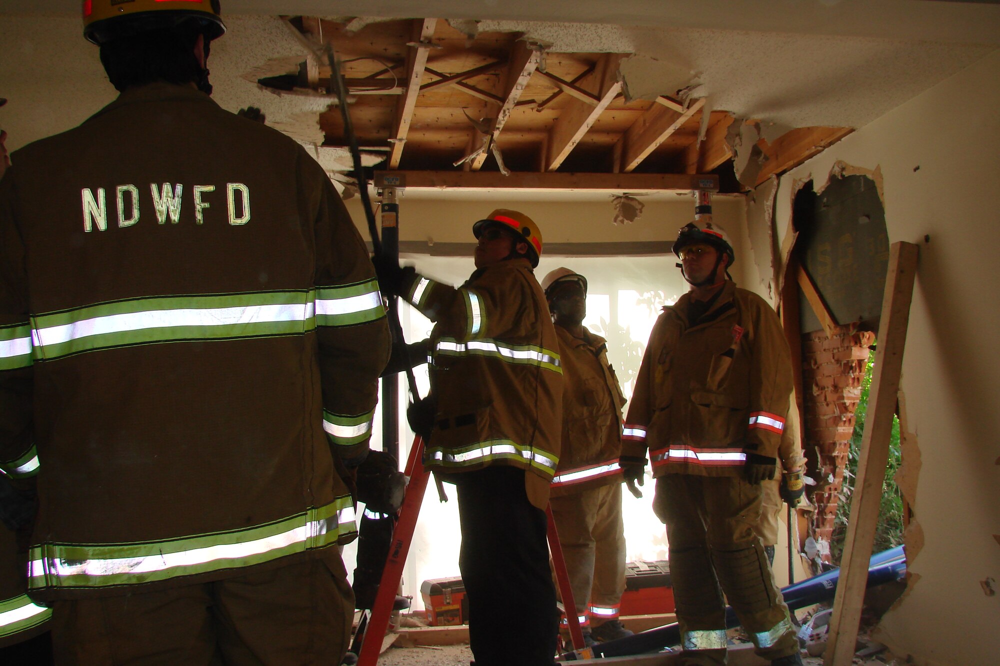 Ray Stokes, Naval District of Washington Fire Department firefighter, uses a hook to pull down ceiling drywall and expose the frames to prepare for building a support structure during a training exercise June 1 on Bolling Air Force Base. The impending demolition of Hickam Village housing created a prime location and opportunity June 1 - 12 for the joint fire department training effort. (U.S. Navy photo by Battalion Chief Michael Tenaglia, NDWFD)