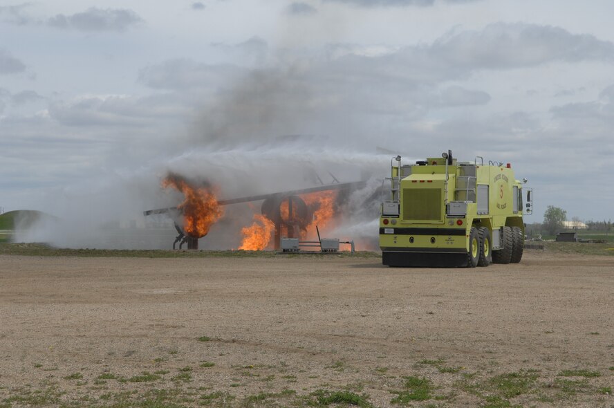 MINOT AIR FORCE BASE, ND – Members from the 5th Civil Engineer Squadron’s Fire Department extinguishes the flames on a simulated crashed plane during a major accident response exercise (MARE) here, June 5.  The exercise was held to further strengthen the base’s ability to respond to an aerial accident, in preparation for the upcoming air show and open house, Northern Neighbors Day, scheduled for July 18 here. (U.S. Air Force photo by Staff Sgt. Angel Gallardo)