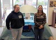 MINOT AIR FORCE BASE, ND – Christina Scott (left), Outdoor Recreation Assistant Manager for the 5th Force Support Squadron, and Rachel Filkins, (right), Outdoor Recreation Manager for the 5th Force Support Squadron, stand in front of the new camping package being offered through the center, here June 8.  The package includes a tent, two sleeping bags, two sleeping pads, a 32-quart cooler, a two- gallon water jug, a lantern, and a cooking stove—all for one flat fee.  This and other packages and services are available to members of Minot Air Force Base at daily, weekly, and weekend prices. (US Air Force photo by Staff Sgt. Keith Ballard)