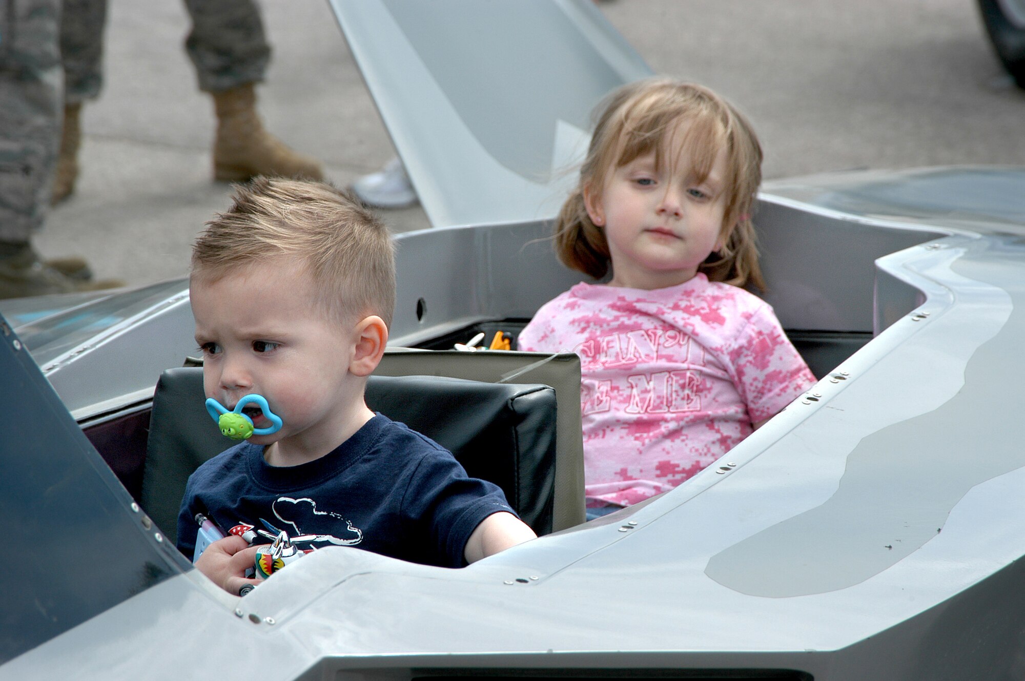 Liam Rainey, 2, and his sister Shayla, 4, sit inside an F-22 mini-jet at the recent Dakota Thunder 2009 Open House and Air Show at Ellsworth Air Force Base, S.D. The children and their father, Senior Airman Noah Rainey, of Ellsworth’s 28th Operations Support Squadron enjoyed aerial performances by the A-10 West Coast Demonstration Team and the U.S. Air Force Thunderbirds. Members of the 343rd Recruiting Squadron supported the air show with recruiting displays and spoke with attendees about Air Force opportunities. More than 40,000 attended the open house and air show to see the U.S. military's air power firsthand and speak with servicemembers about what they do and why they serve. (U.S. Air Force photo/Tech. Sgt. David J. McCarrison)