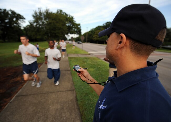 Tech. Sgt. Shawn McKeen announces runtimes as Airmen cross the finish line at the Commander's Fitness Challenge 5K run here June 5. More than 350 Airmen from various units participated in the run. Sergeant McKeen is the fitness NCO in charge for the 437th Force Support Squadron. (U.S. Air Force photo/Senior Airman Timothy Taylor)