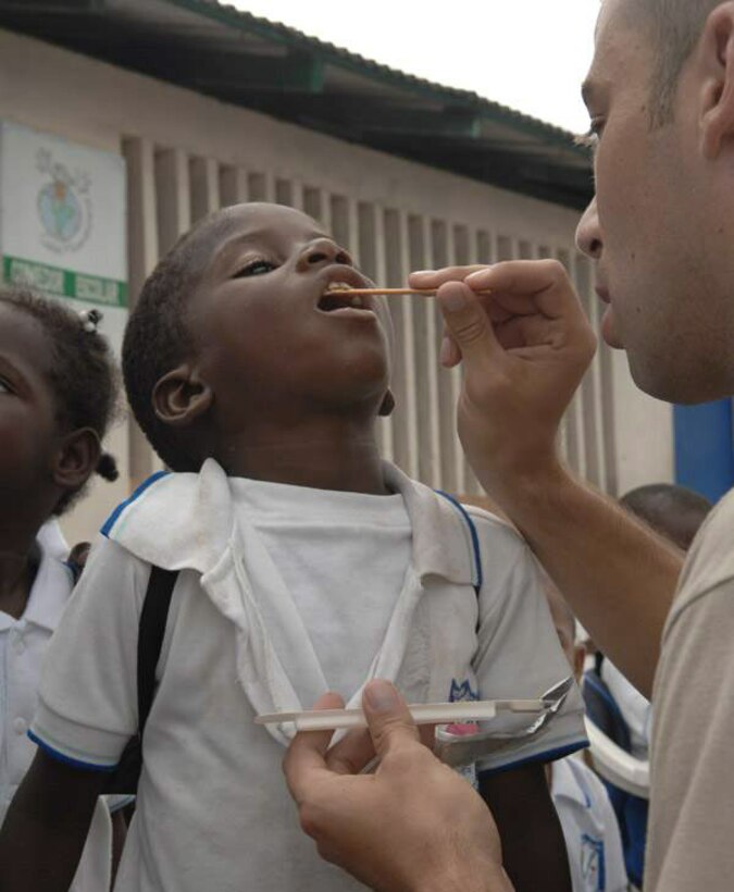 Senior Airman David Evans assists dental professionals with fluoride treatment after a band performance June 10 at Tumaco, Colombia. The band performed for the students, and then the children were taught the importance of dental hygiene at the Cuidadela Mixtra Escuela as part of Continuing Promise 2009. The humanitarian mission combines U.S. military and interagency personnel, nongovernmental organizations, civil service mariners, academics and partner nations to provide medical, dental, veterinary and engineering services afloat and ashore alongside host nation personnel. Airman Evans is an Air Force South Band member deployed with Military Sealift Command hospital ship USNS Comfort. (Defense Department photo/Senior Airman Jessica Snow)