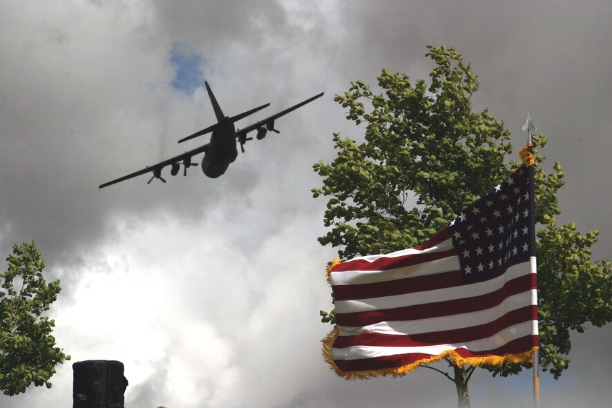 A C-130 Hercules flies over the American flag at the Iron Mike Memorial Ceremony June 7, 2009, at La Fiere, France. Hundreds visit every year to honor those who sacrificed during D-Day and World War II on this very same field. (U.S. Army photo/Lea Greene) 

