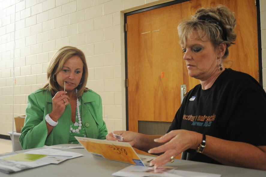 Twonana Campbell, (right) a volunteer, assists Sandra Ely during the bone marrow  registration process at the Goldsboro Police Department gym, June 9, 2009. The registration process includes filling out paperwork on health history and swabbing the inside of each cheek. Cheek cells are used to determine a match for a future patient in need of a bone marrow transplant. (U. S. Air Force photo by Airman 1st Class Whitney S. Lambert)