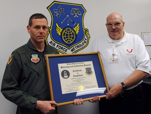 WHITEMAN AIR FORCE BASE, Mo. – Chief Master Sgt. (Ret.) Edward Randall, Precision Measurement Equipment Laboratory site manager accepts the Certificate of Compliance for Whiteman’s Precision Measurement Equipment Laboratory from Colonel Robert Wheeler, 509th Bomb Wing commander. PMEL recently completed their biennial certification by the Air Force Metrology and Calibration program office. (US Air Force Photo/SrA Jason Huddleston)