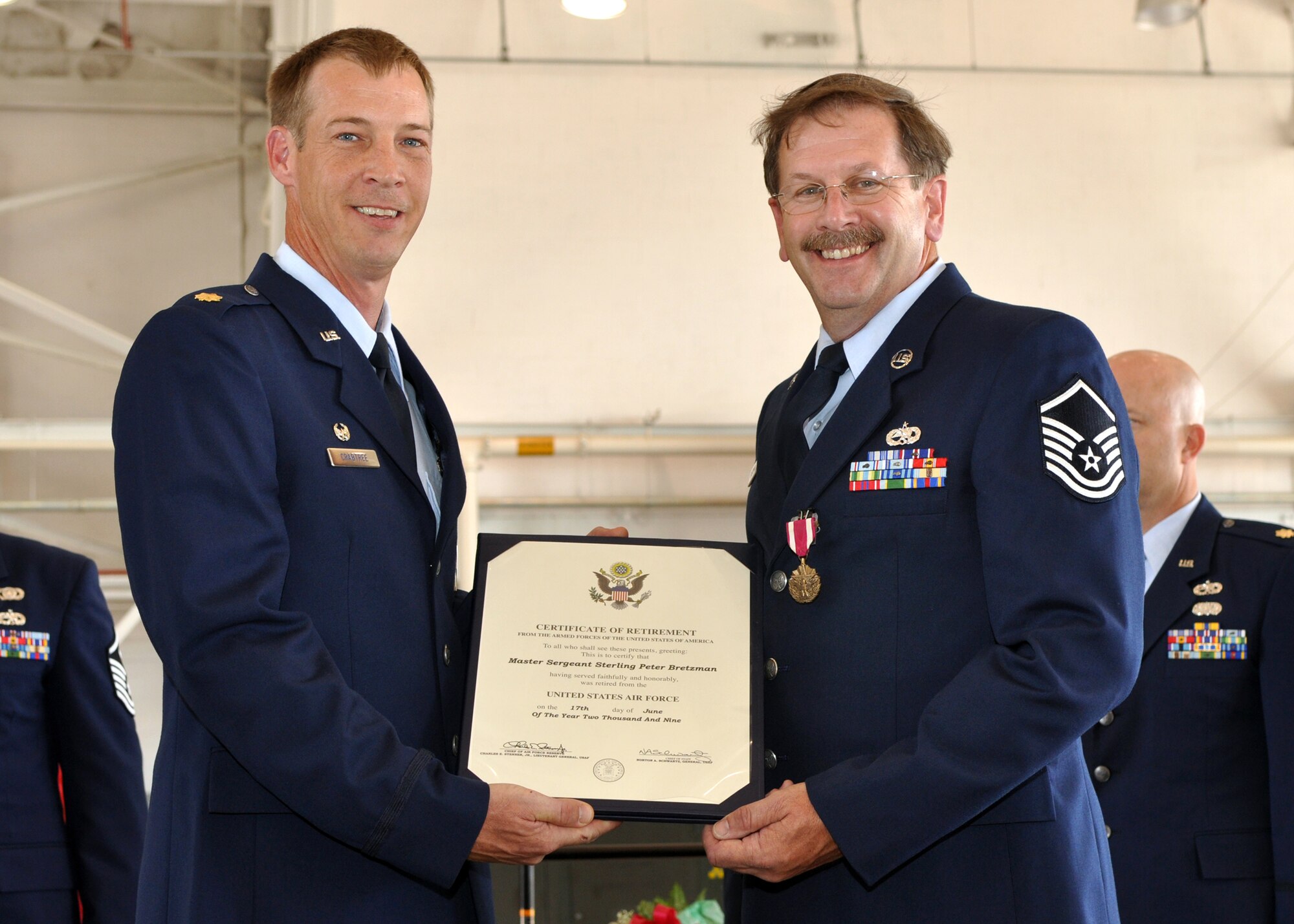 Master Sgt. (Ret) Sterling “Pete” Bretzman receives his retirement certificate from Maj. Warren Crabtree, 917th Maintenance Operations Squadron, commander, during one of the retirement ceremonies held in the A-10 Hangar at Barksdale Air Force Base, La., June 6, 2009. Master Sgt Bretzman is one of three Airmen from the 917th Wing who retired on the anniversary of the D-Day invasion of June 6, 1944. The retirements mean a loss of more than 101 years of total experience to the 917th Wing. Master Sgt. Bretzman retired after 37 years of service. Also retiring were Master Sgt. James Guggenheim with 31.5 years of service and Technical Sgt. Thomas Goerner with 33 years of service. (U.S. Air Force photo/Tech. Sgt. Jeff Walston)    