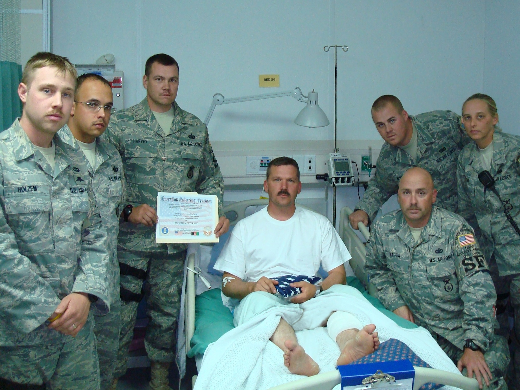 Staff Sgt. Brian Wunder and members of the 128th Air Refueling Wing's Security Forces Squadron present a folded flag and accompanying certificate to Staff Sgt. Brian Peterson as part of the Flags for Wounded Troops program.  The program, conducted from Bagram Air Base, Afghanistan, recognizes U.S. service members wounded in the line of duty, and is a secondary recognition event which followed the presentation of the Purple Heart medal.  (U.S. Air Force photo)