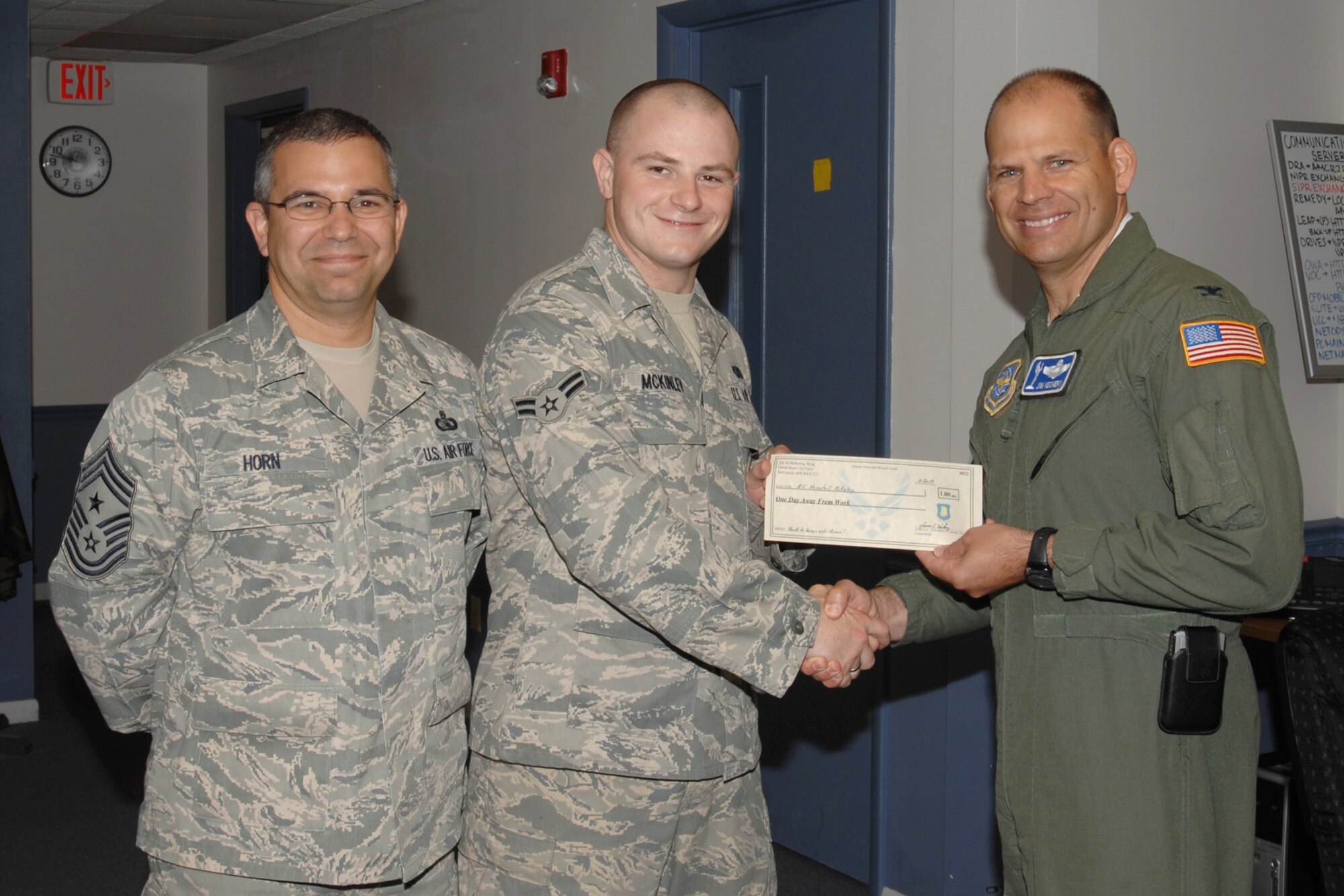 MCCONNELL AIR FORCE BASE, Kan. -- Col. James C. Vechery, 22nd Air Refueling Wing commander, recognizes Airman 1st Class Herschell McKinley, 22nd Communications Squadron, with the first “An Airman Above and Beyond Award” at the Comm Focal Point, June 10. Colonel Vechery, rewards Airmen who are observed doing things above and beyond their normal duties, by awarding them a one day pass. (Photo by Staff Sgt. Jamie Train)