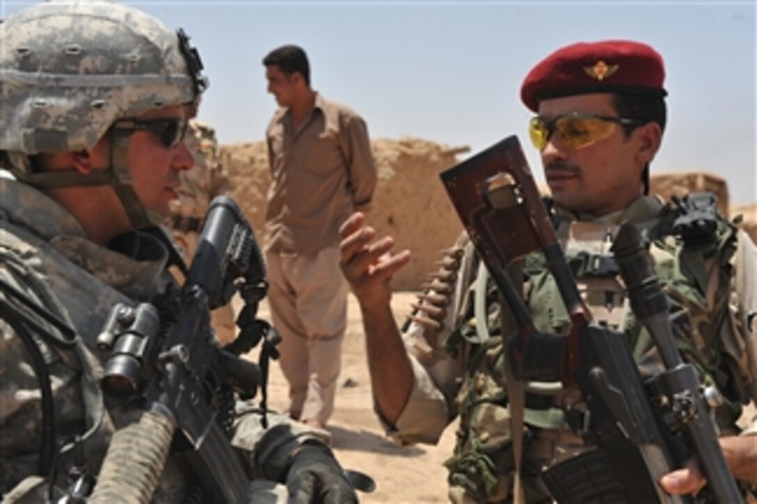 U.S. Army Sgt. Jose Lugo from 3rd Platoon, Charlie Company, 1st Battalion, 8th Cavalry Regiment, 2nd Brigade Combat Team, 1st Cavalry Division talks with an Iraqi soldier in the village of Raml in Kirkuk, Iraq, on June 4, 2009.  U.S. Coalition and Iraqi Security Forces are working to identify areas that need road repair in and around Kirkuk, Iraq.  