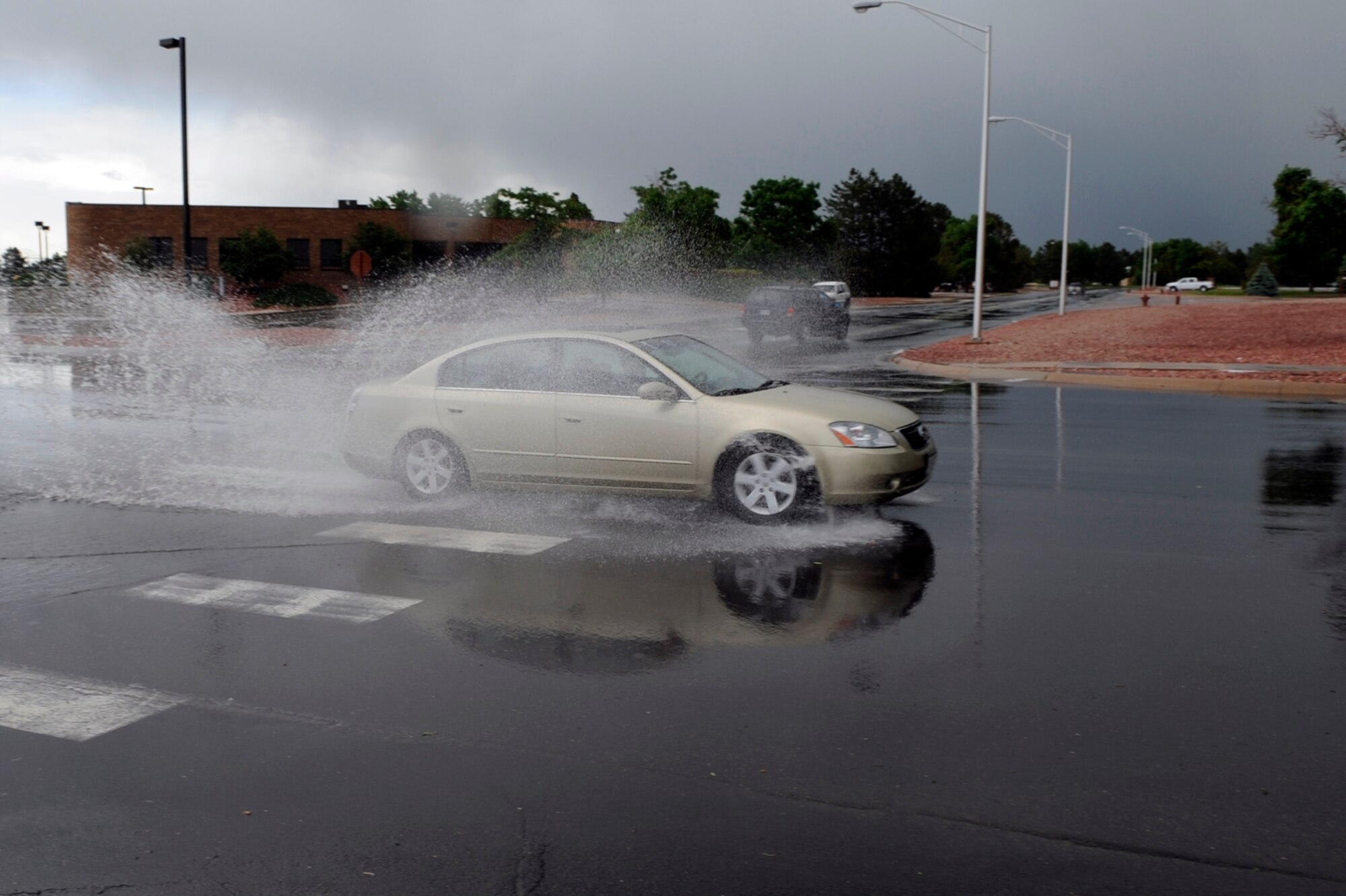 A driver heading east through the intersection at Stewart Avenue and Otis Street navigates through a large puddle left in the wake of a short hailstorm that pounded Peterson at approximately 2 p.m., June 11. During the storm, drivers were forced to contend with puddles and gravel-sized hail. There were no reports of any base damage caused by the squall. (Air Force photo by Rob Bussard)