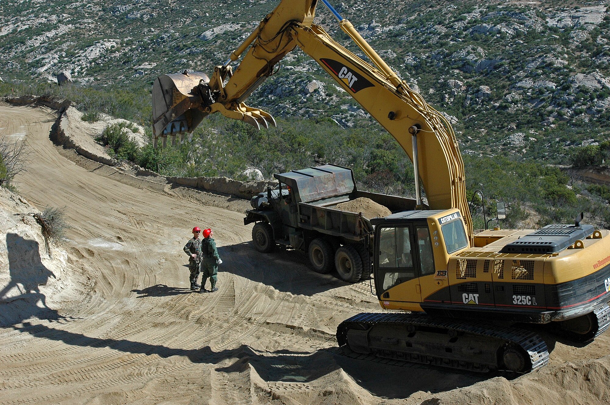 Under the shadow of a large excavator, Staff Sgt. Mark Ellis and Master Sgt. Chris Blackwell discuss plans to smooth out this dangerous stretch of hairpin turns that hamper Border Patrol officers in their efforts to secure the border May 1, 2008 near Campo, Calif. Sergeants Ellis and Blackwell are airfield crew specialists from the 201st RED HORSE Squadron from Fort Indiantown Gap, Pa.  (Photo by Capt. Jay Ostrich)