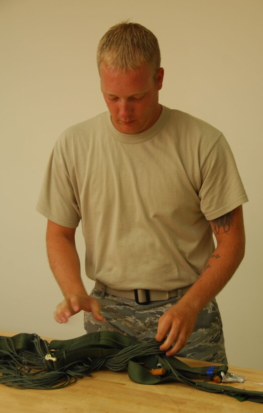 ANDERSEN AIR FORCE BASE, Guam - Staff Sgt. Christopher Kitts, 36th Operations Support Squadron, untangles suspension lines on a parachute here June 3. Sergeant Kitts maintains more than 560 equipment assets, including helmets, masks, harnesses, G-suits and various types of parachutes. (U.S. Air Force photo by Senior Airman Shane Dunaway)
