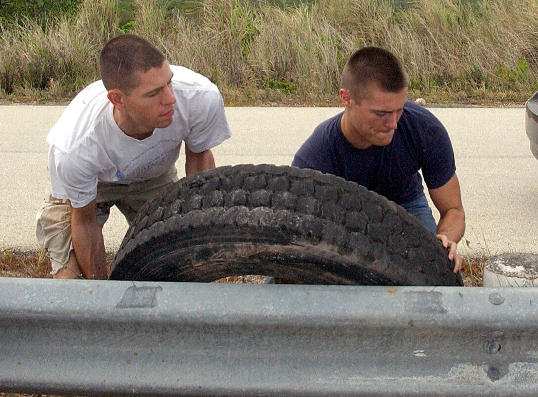 ANDERSEN AIR FORCE BASE, Guam - Senior Airman Brian Quay and Senior Airman Andrew Hughes, both members of the 644th Combat Communications Squadron, move a tire during the Big Brother Big Sister Soap Box Derby set-up April 28. Airman Hughes was selected as Andersen's 'Top Performer' by Master Sgt. Anthony Cruz-Munoz, 644th CBCS first sergeant, for his dedication to fitness, education, volunteerism and his job. (U.S. Air Force photo by Airman Carissa Wolff)