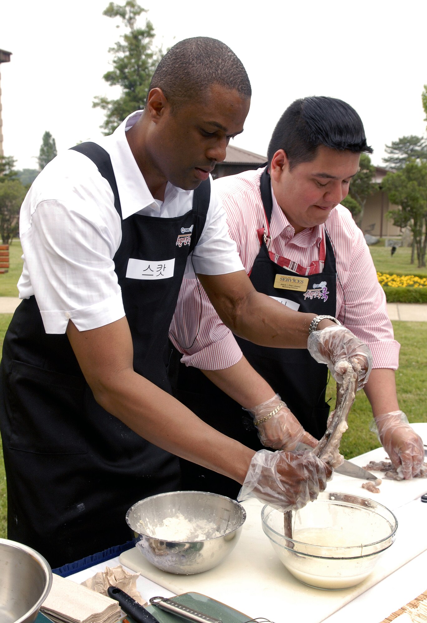 Master Sgt. Andre Scott, handles a live octopus while Jesse Diaz, chops up ingredients during the filming of Delicious Korea, (Dae Han Min Guk) on Osan Air Base June 8. The South Korean television studio filmed Team Osan members as they prepared traditional South Korean meals. This is the first time United States military members have been in the show. Sergeant Scott is a member of the 51st Security Forces Squadron and Mr. Diaz is the the marketing director for the 51st Services Squadron. (U.S. Air Force photo/Senior Airman Stephenie Wade).