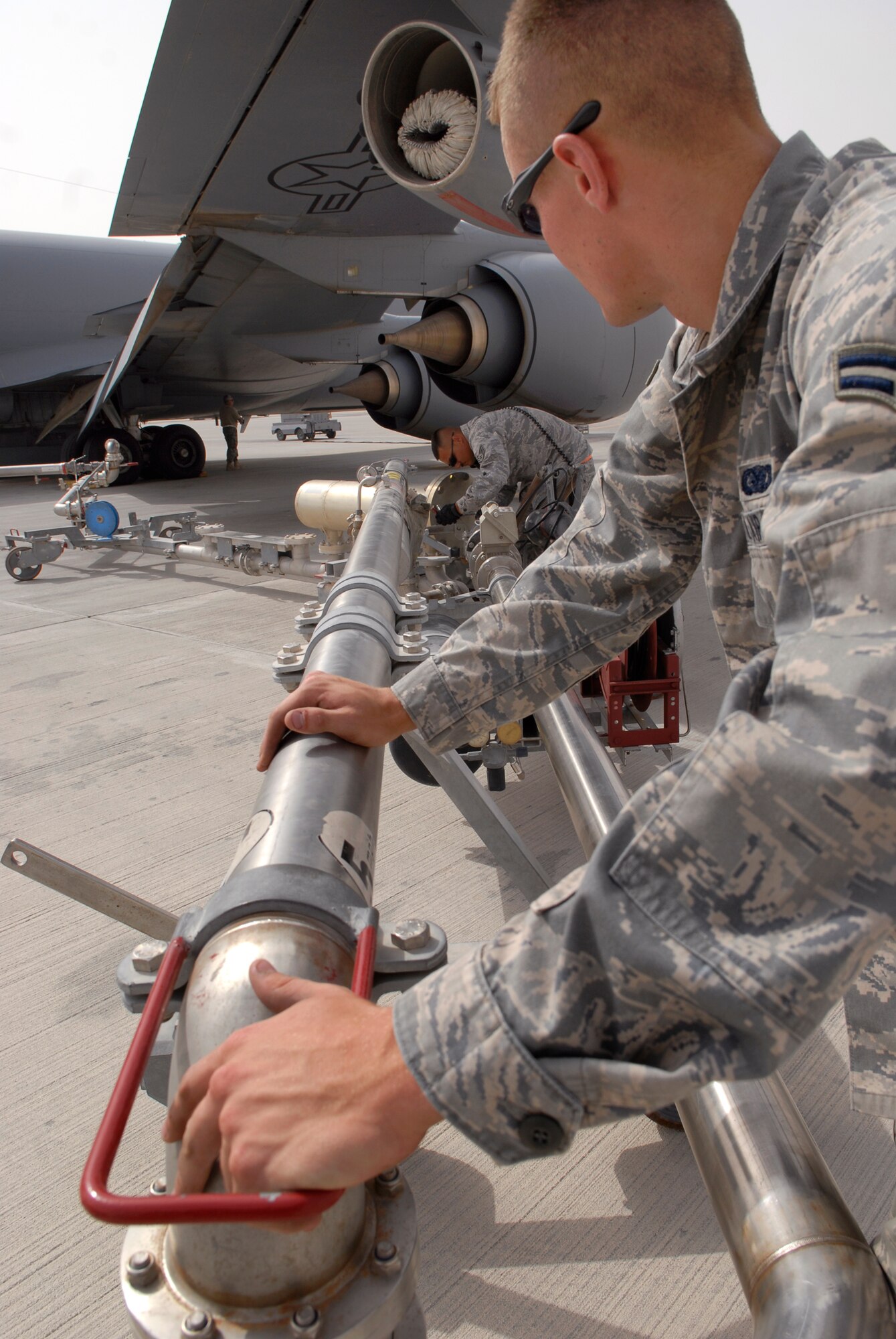 Staff Sgt. David Thomas, 379th Expeditionary Logistics Readiness Squadron (ELRS) fuels distribution supervisor, and Airman 1st Class Brandon Sullivan (near), a 379th ELRS fuels distribution operator, move a refueling pantograph into position to refuel a KC-135R Stratotanker, June 10, 2009, at an undisclosed location in Southwest Asia.  Airman Sullivan pumped 16,083 gallons of JP-8 fuel at 457 gallons per minute through the system to refuel the aircraft.  Fuel distribution operators deliver fuel to aircraft around the clock everyday of the year to meet the ongoing demands of the mission.  Sergeant Thomas hails from Mountain Ranch, Calif. and is deployed from Holloman Air Force Base, N.M.  Airman Sullivan hails from Burlington, Iowa and is deployed from Kadena Air Base, Japan.  Both are deployed in support of Operations Iraqi and Enduring Freedom and Combined Joint Task Force - Horn of Africa.  (U.S. Air Force photo/Senior Airman Andrew Satran/released)  