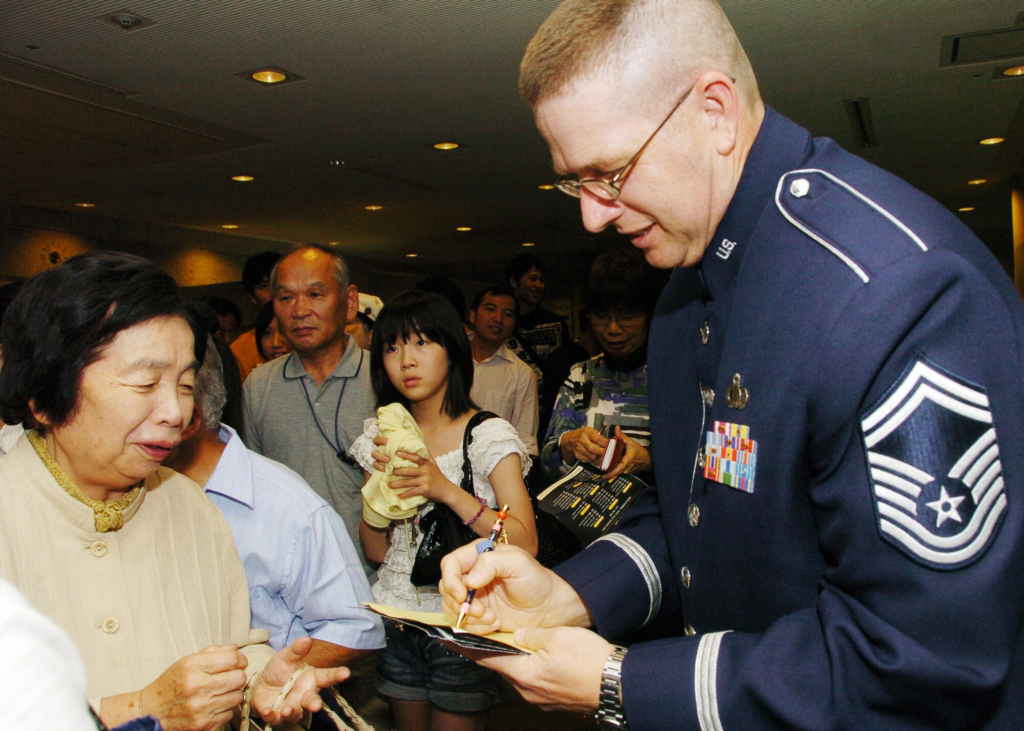 MIZUHO, Japan -- Senior Master Sgt. Daniel Smalley, U.S. Air Force Band of the Pacific-Asia, signs autographs June 14 following a concert by the Mizuho Youth Symphonic Band at the Mizuho Viewpark Sky Hall. Sergeant Smalley sang a variety of numbers, including "I Left My Heart in San Francisco" and "New York, New York" for a crowd of more than 300. (U.S. Air Force photo/Master Sgt. Matt Summers)