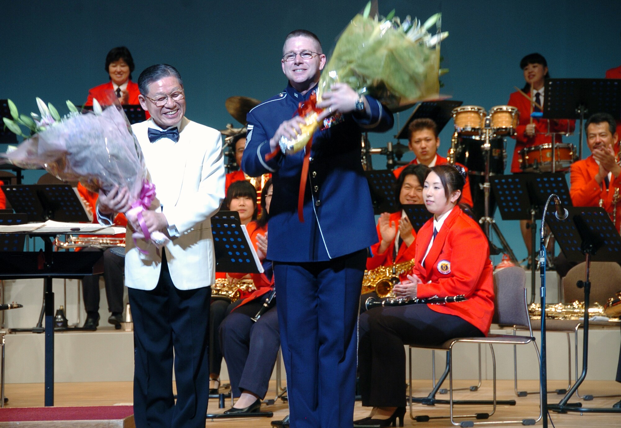 MIZUHO, Japan -- Conductor Hisatoshi Muta (left) and Senior Master Sgt. Daniel Smalley, U.S. Air Force Band of the Pacific-Asia, make a curtain call June 14 following a concert by the Mizuho Youth Symphonic Band at the Mizuho Viewpark Sky Hall. Sergeant Smalley sang a variety of numbers, including "I Left My Heart in San Francisco" and "New York, New York" for a crowd of more than 300. (U.S. Air Force photo/Master Sgt. Matt Summers) 