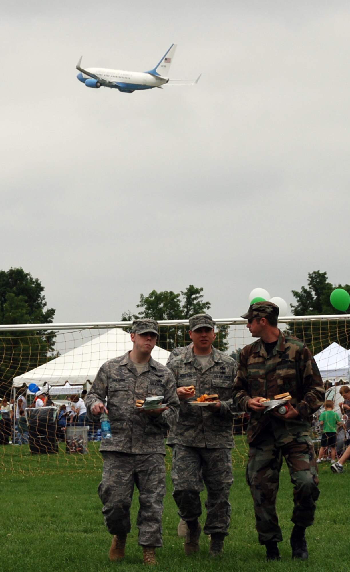 A C-40C plane from the 932nd Airlift Wing makes a pass as military members eat lunch below during a picnic.  The wing flies both the C-9C and C-40C on distinguished visitor missions.  (U.S. Air Force photo/Maj. Stan Paregien)