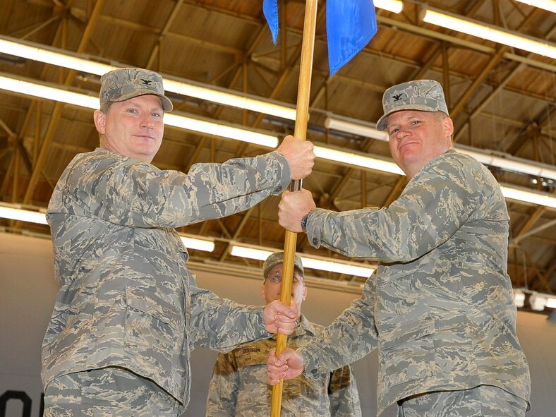 Col. Robert Thomas, 92nd Air Refueling Wing commander, passes the 92nd Maintenance Group guidon to Col. John Tobin, 92nd MXG commander, during the Change of Command ceremony in hangar 2050 May 27. During the ceremony Colonel Tobin spoke of the pride that comes along with becoming the 92nd MXG commander. (U.S. Air Force photo / Airman 1st Class Melissa L. Carlino)