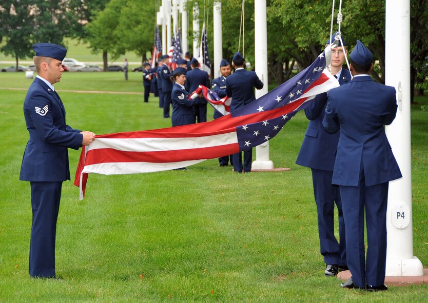 OFFUTT AIR FORCE BASE, Neb. -- Staff Sgt. Adam Henderson from the 55th Aircraft Maintenance Squadron, holds an American flag as Airman Douglas Merklinger (wearing glasses) and Senior Airman Lorenzo Chooran also with the 55th Aircraft Maintenance Squadron, hoist an American flag up a flag pole during Offutt's Flag Day ceremony at the parade grounds here June 12. During the ceremony, a 78-member flag detail raised 26 American flags. U.S. Air Force Photo by Jeff W. Gates