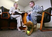 5/14/2009 - Sharon Witter and Master Sgt. Don Friemel, both with the 37th Mission Support Squadron, go over paperwork while Aamee plays with a tennis ball. The Airman and Family Readiness Flight is fostering Aamee, exposing her to a variety of social settings, and caring for her until she is ready for Military Working Dog training. (U.S. Air Force photo/Robbin Cresswell)
