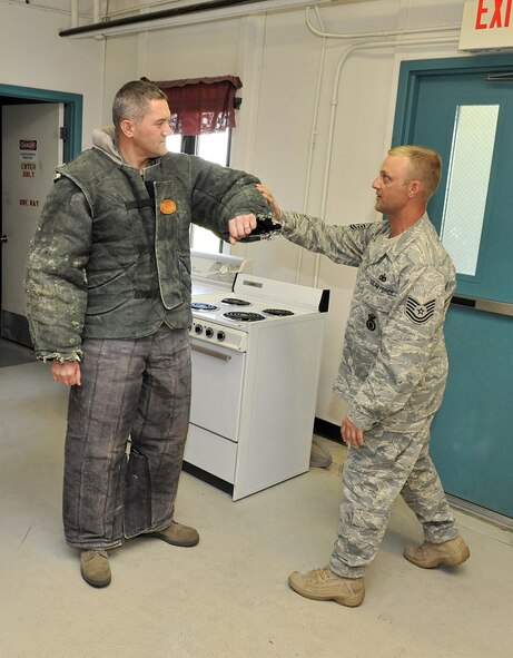 Tech. Sgt. Todd Smith, NCOIC of the Military Working Dogs section, explains to Col. Paul Gydesen, 341st Missile Wing vice commander, how the dog will attack him. Colonel Gydesen spent his "out and about" time with the K-9 unit June 3. (U.S. Air Force photo/John Turner)